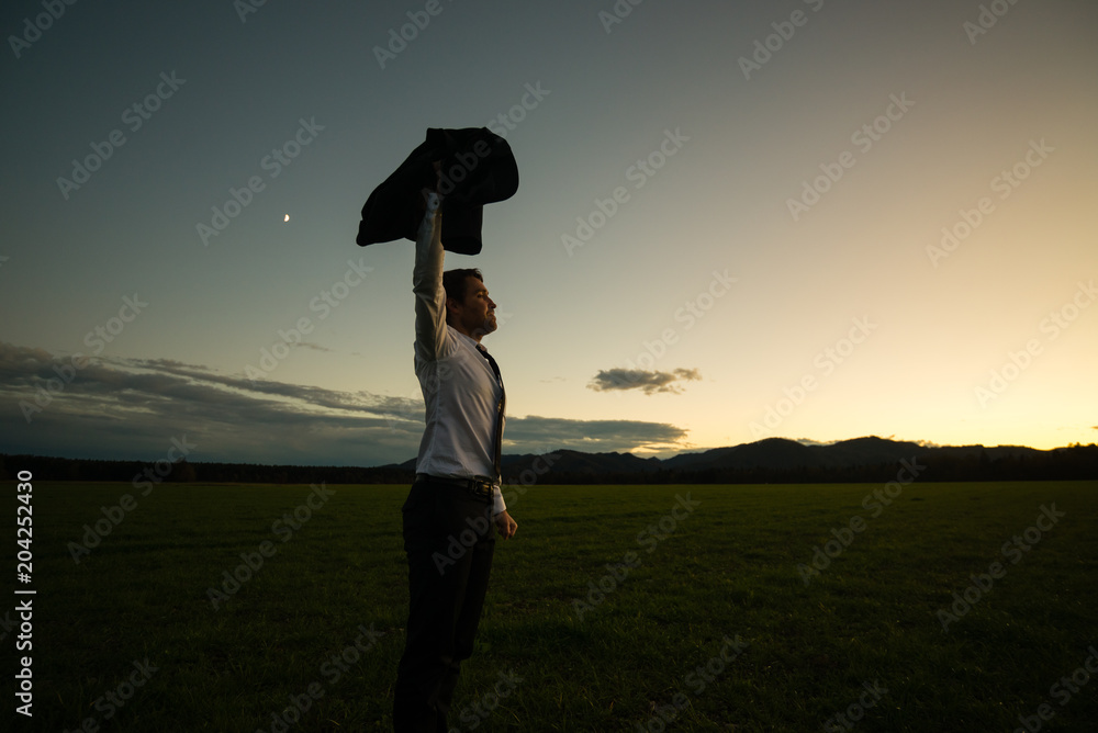 Businessman Standing in the Field and Raising his Arm with Coat