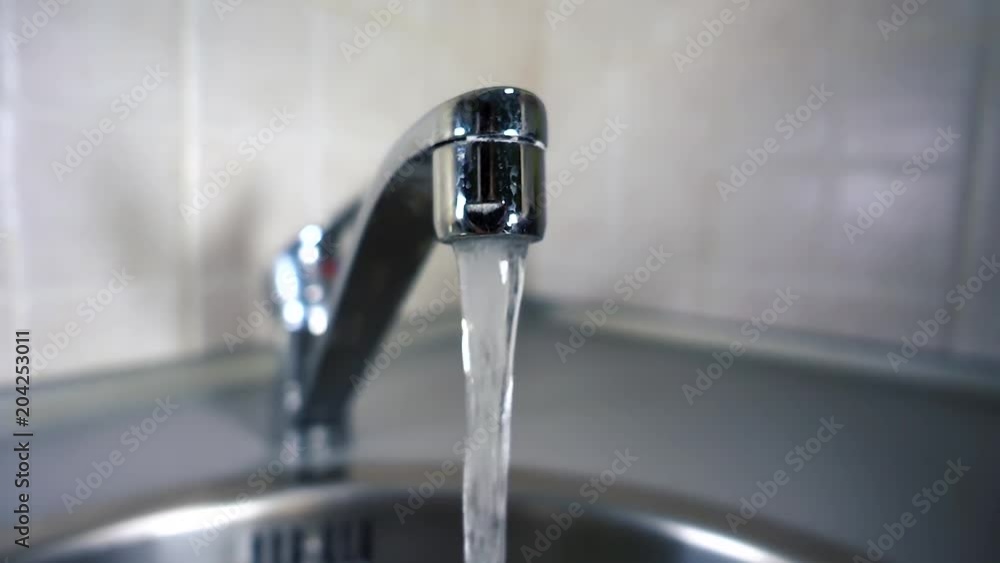 Woman opens water tap. Tap water flows from tap in kitchen in slow motion. City life modern human. Videography of home life. Woman opens water tap. Tap water flows from tap in kitchen in slow motion. City life modern human. Videography of home life.