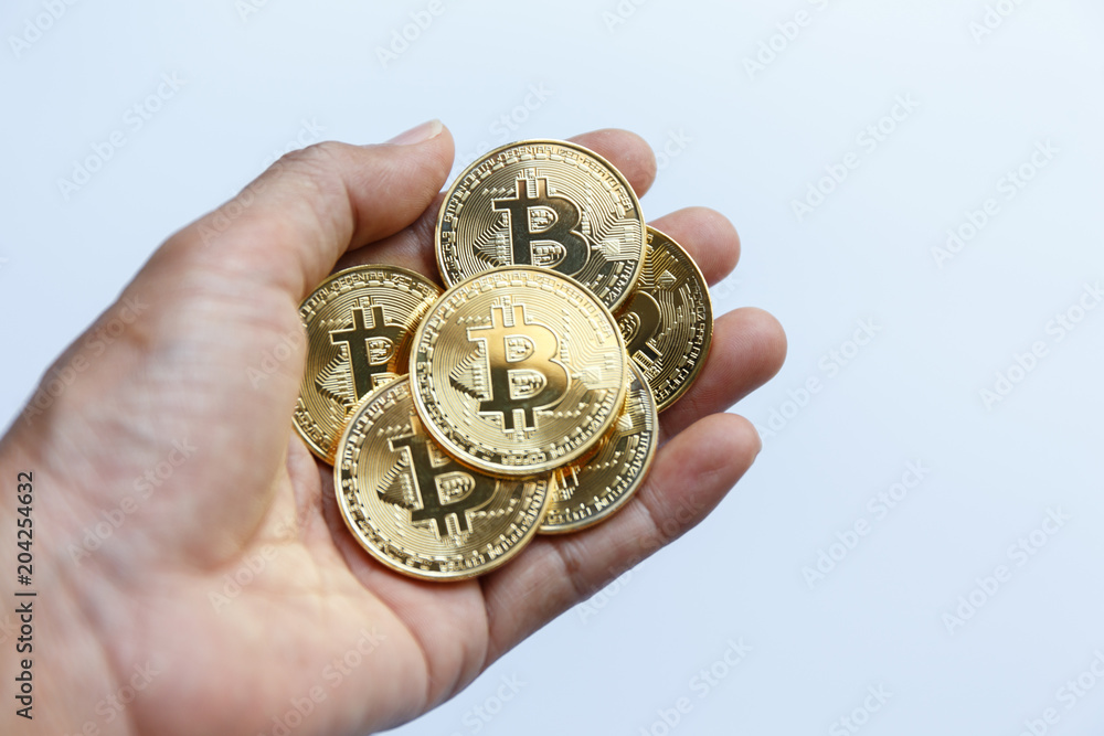 A hand holding Golden bitcoin virtual money on white background. A hand holding Golden bitcoin virtual money on white background.
