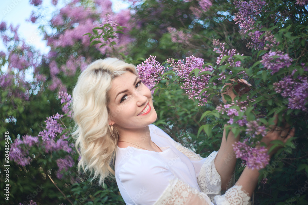 Fototapeta premium Beautiful woman in a spring garden with blooming lilacs.