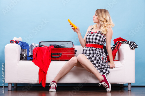 Young woman packing suitcase on couch