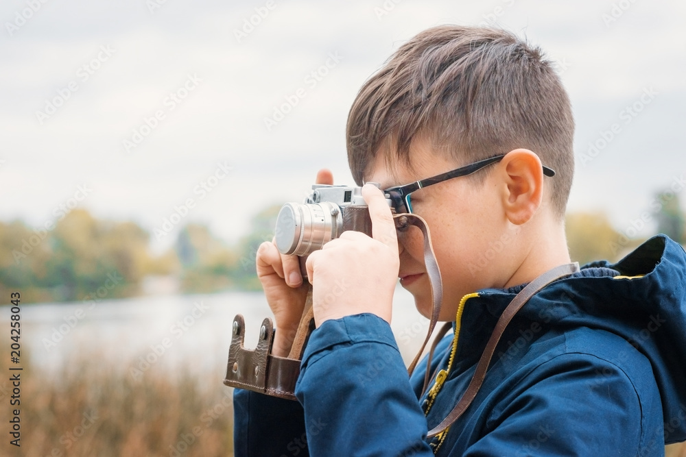 Boy child outdoors holding an old camera.