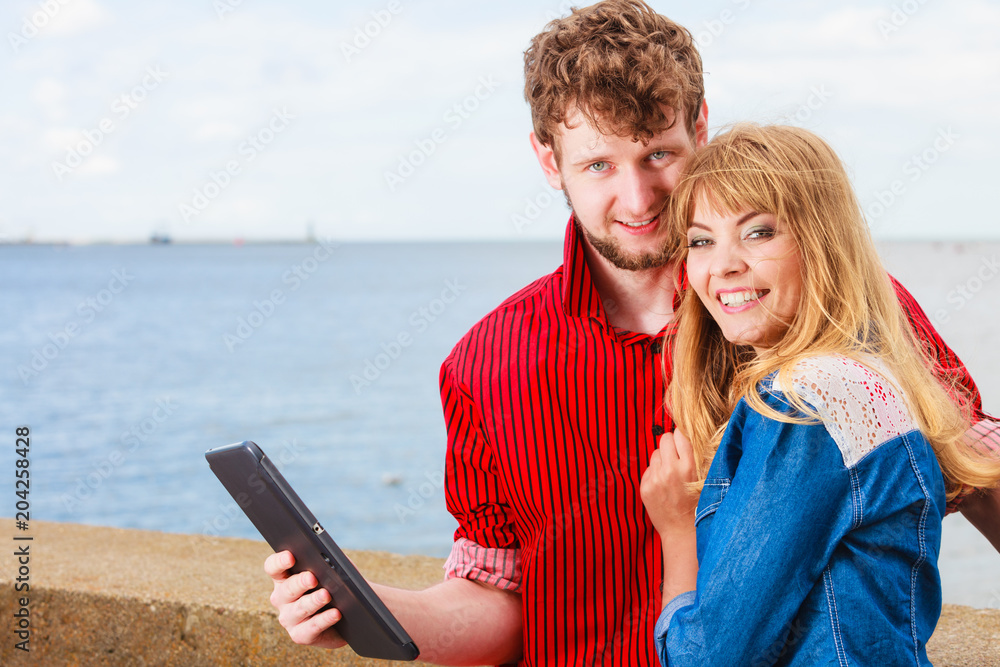 Young couple with tablet by seaside outdoor