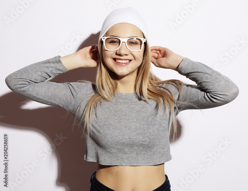 Lifestyle and people concept: Young cute smiling hipster girl wearing white glasses and hat. Emotion on face.