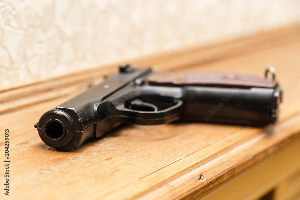 Obraz premium Black pistol on a wooden background