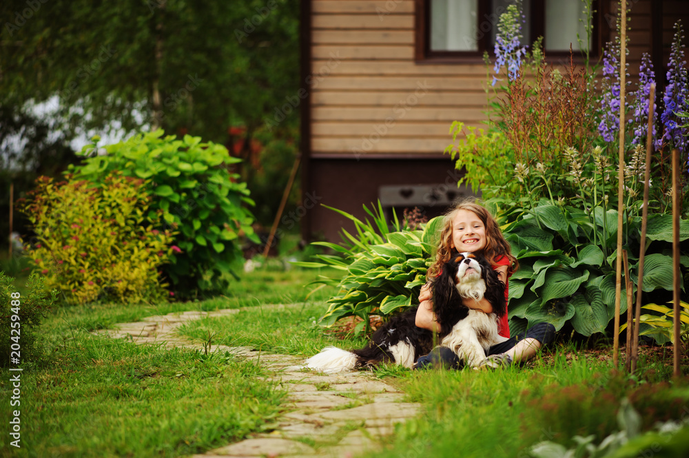 happy 8 years old child girl playing with her spaniel dog outdoor in summer garden happy 8 years old child girl playing with her spaniel dog outdoor in summer garden