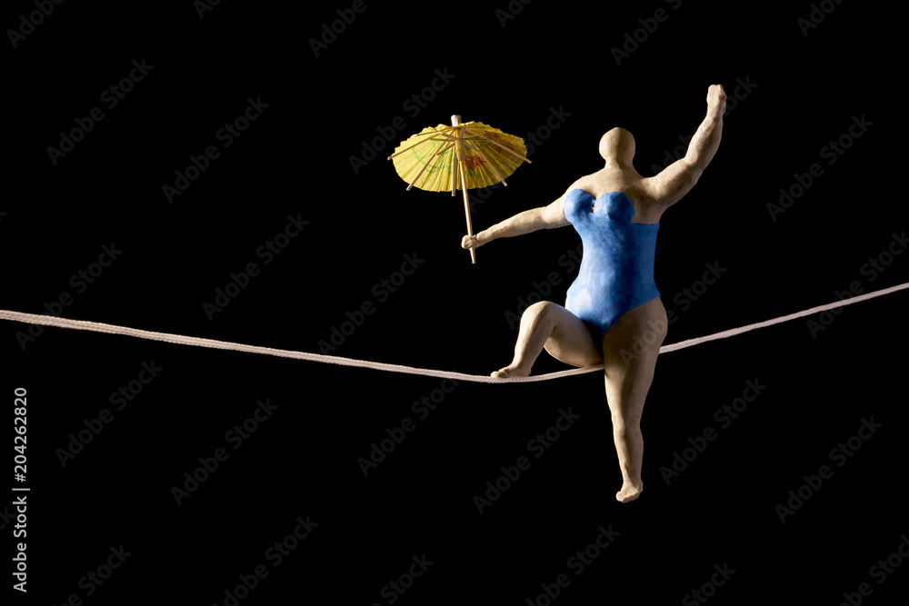 Fat woman tightrope walker with an umbrella. Isolated on black background.  With copy space text. Studio Shot. Stock Photo