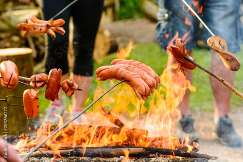 Grilling sausages over a campfire in the forest. Holiday and summer camping in the countryside. Beltaine night in the Czech Republic. May day celebrations. 