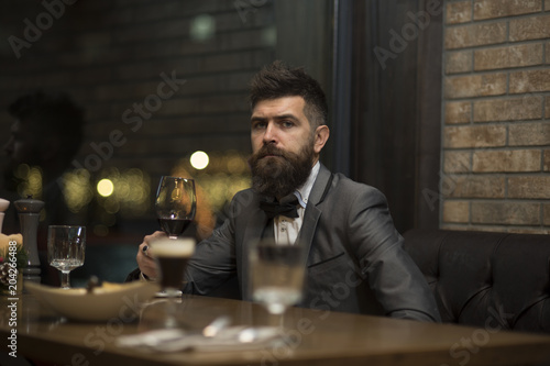 Date meeting of hipster awaiting in pub. Perfect wine. Businessman with long beard drink in cigar club. Bearded man rest in restaurant with wine glass. bar customer sit in cafe drinking alcohol.