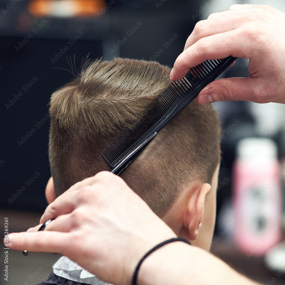 © Artem - Hairdresser is making haircut to boy in barbershop. Back view. © Artem - Hairdresser is making haircut to boy in barbershop. Back view.