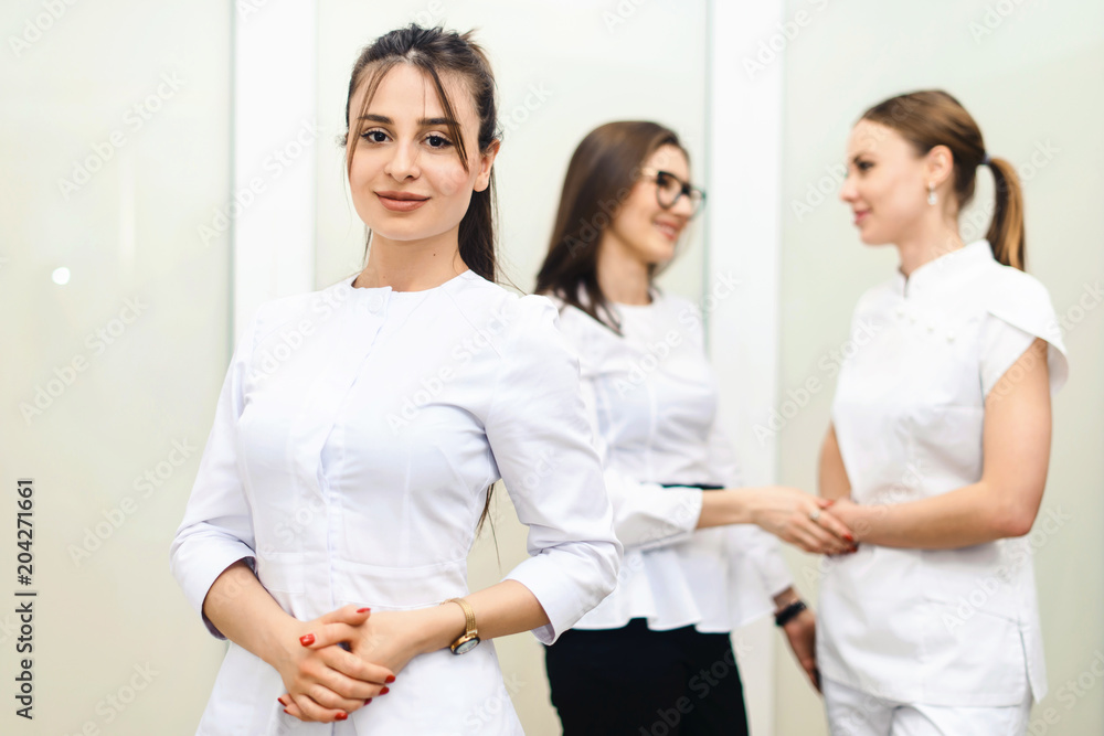 Cheerful group of young dentists and their assistants standing in the dental office and looking at camera and friendly smiling at white background of medical room. Cheerful group of young dentists and their assistants standing in the dental office and looking at camera and friendly smiling at white background of medical room.