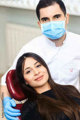 Portrait of young smiling dentists and female patient in dental stomatology clinic with white background