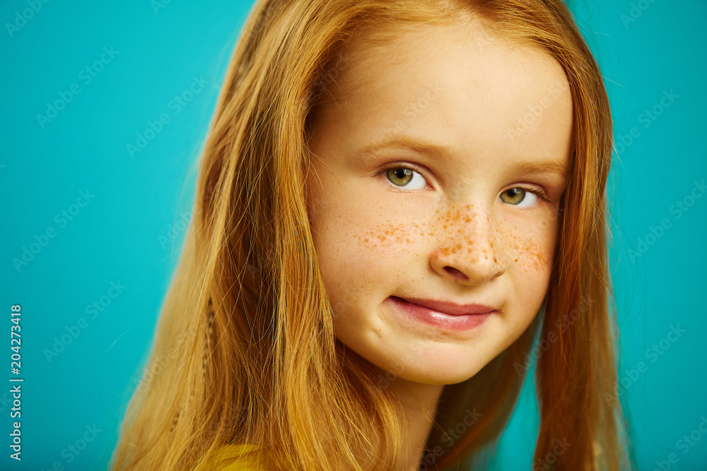 Close up portrait of beautiful redhead children girl with cute freckles on blue isolated. Close up portrait of beautiful redhead children girl with cute freckles on blue isolated.