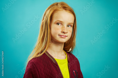 Bild auf Leinwand Portrait of red haired child girl in uniform on blue isolated.
