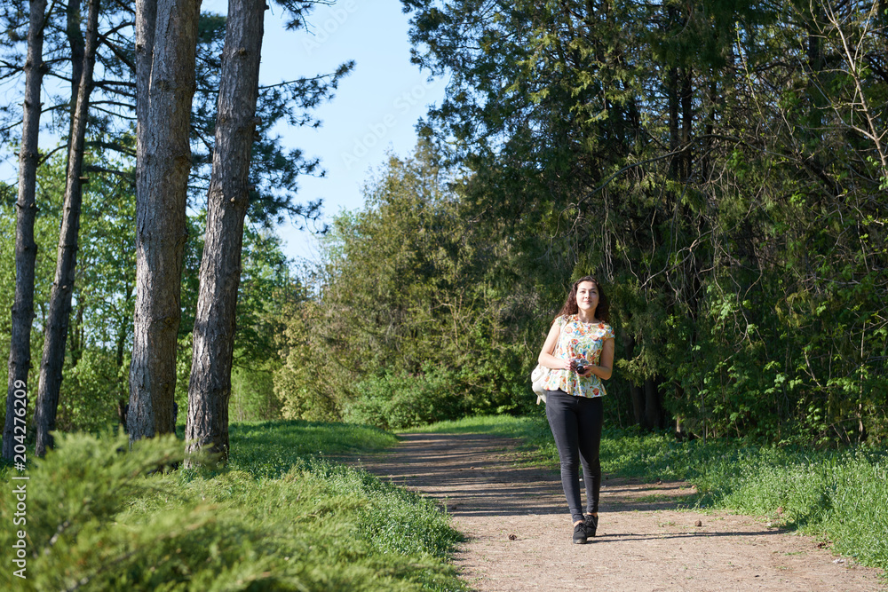 young girl walking in spring forest with camera and taking pictures young girl walking in spring forest with camera and taking pictures