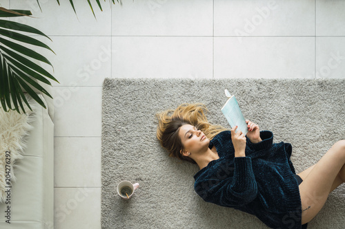 Woman with coffee and book on carpet photo