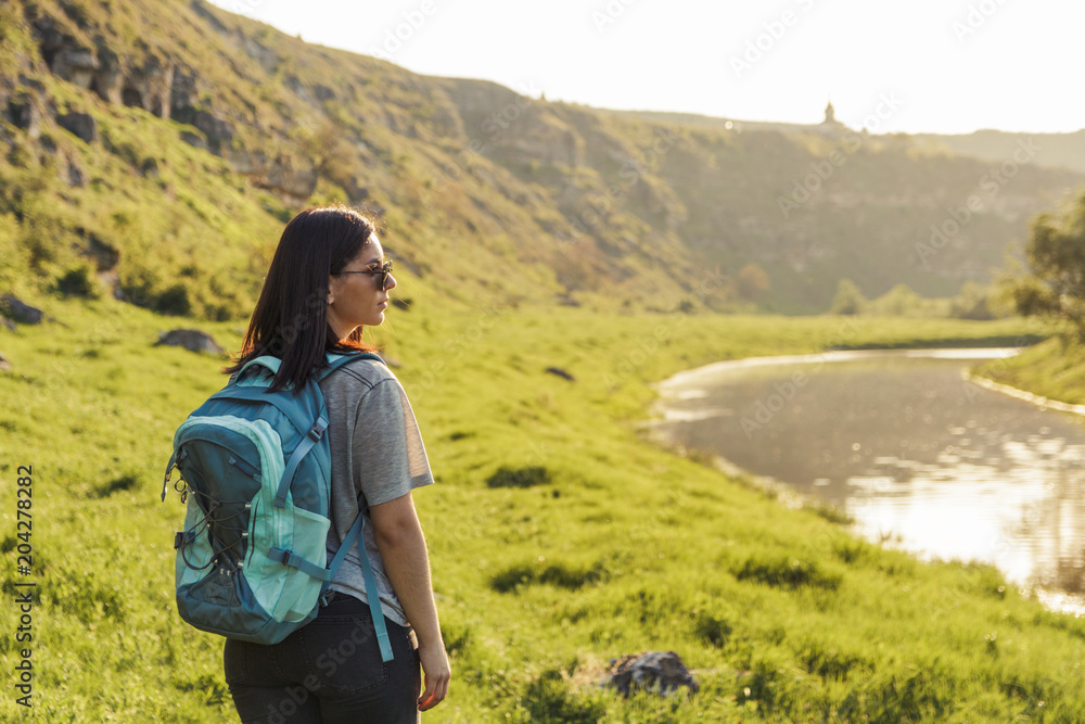 Traveler Woman with backpack looking landscape view at nature green field at sunset, tourism concept