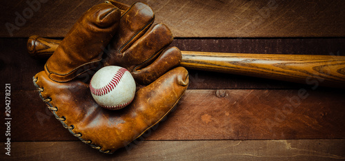 Fotografie A group of vintage baseball equipment, bats, gloves, baseballs on wooden backgro