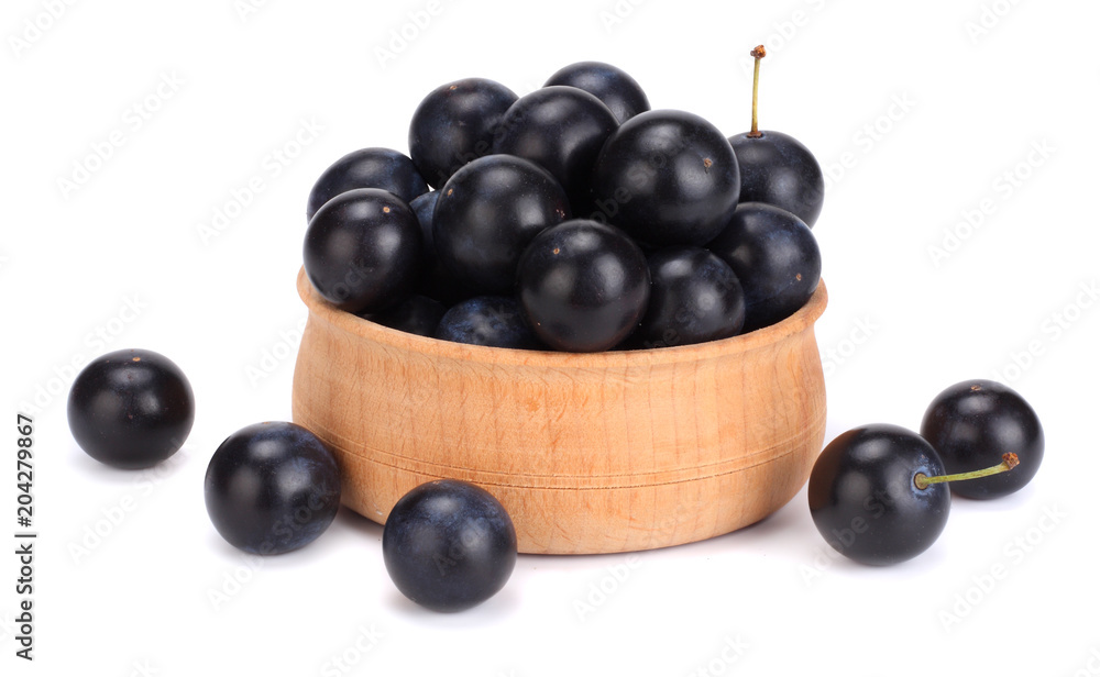 blackthorn berries in wooden bowl with green leaf isolated on white background blackthorn berries in wooden bowl with green leaf isolated on white background