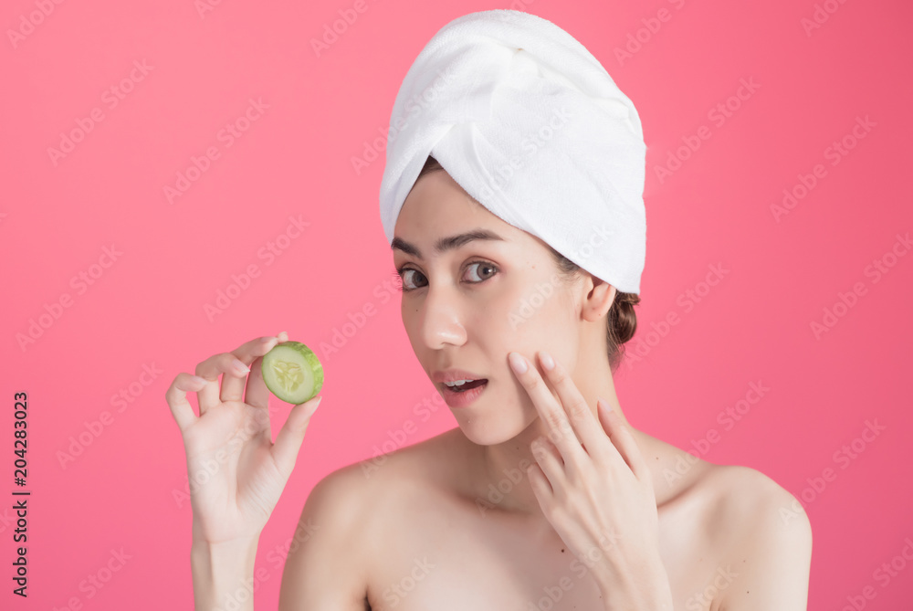 beautiful asia woman with towel on head with perfect clean skin smiling holding cucumber slices over pink background. Beauty cosmetology and spa. beautiful asia woman with towel on head with perfect clean skin smiling holding cucumber slices over pink background. Beauty cosmetology and spa.