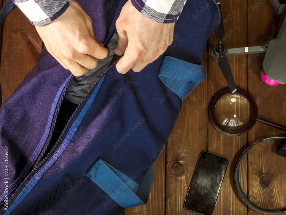 close up hand holding travel bag on the wooden table with accessories