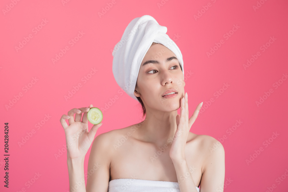 beautiful asia woman with towel on head with perfect clean skin smiling holding cucumber slices over pink background. Beauty cosmetology and spa. beautiful asia woman with towel on head with perfect clean skin smiling holding cucumber slices over pink background. Beauty cosmetology and spa.
