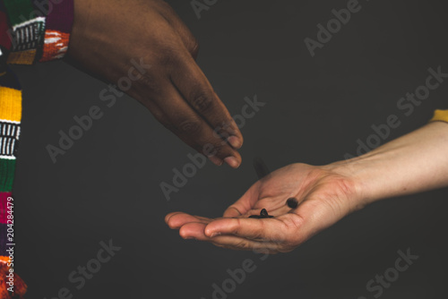 Racially divergent hands sharing coffee beans