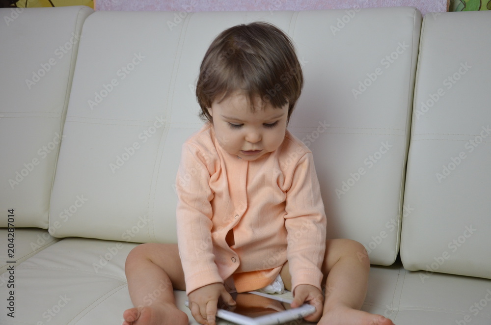 Toddler boy playing with digital tablet on couch at home Toddler boy playing with digital tablet on couch at home