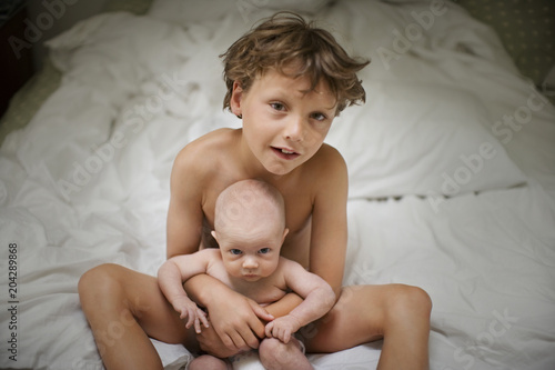 View of a small boy sitting with a baby.