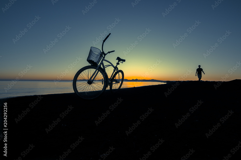 Obraz premium silueta de bicicleta y hombre caminando en la bahía
