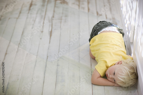 Young boy curled up on the floor.