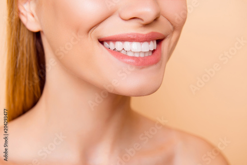 Closeup cropped half face portrait of attractive, turned, nude, natural, perfect, ideal girl with healthy white teeth isolated on beige background, perfection, wellness, wellbeing, restoration concept