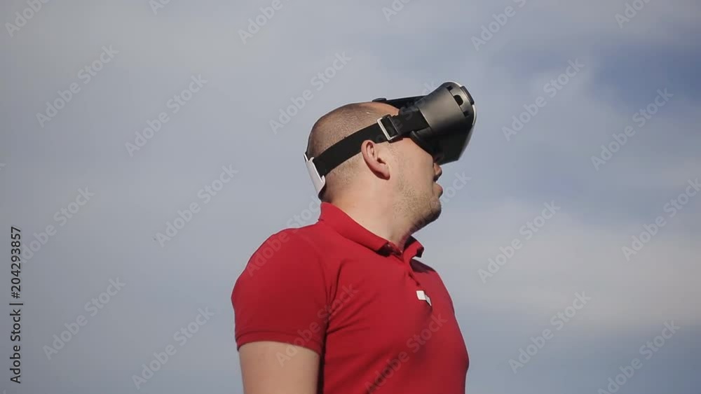 man uses a virtual reality glasses on the background of blue sky man uses a virtual reality glasses on the background of blue sky