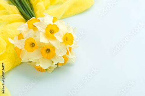 Fototapeta Naklejka Na Ścianę i Meble -  Daffodil bouquet with yellow textile decoration on blue pastel background with copy space.