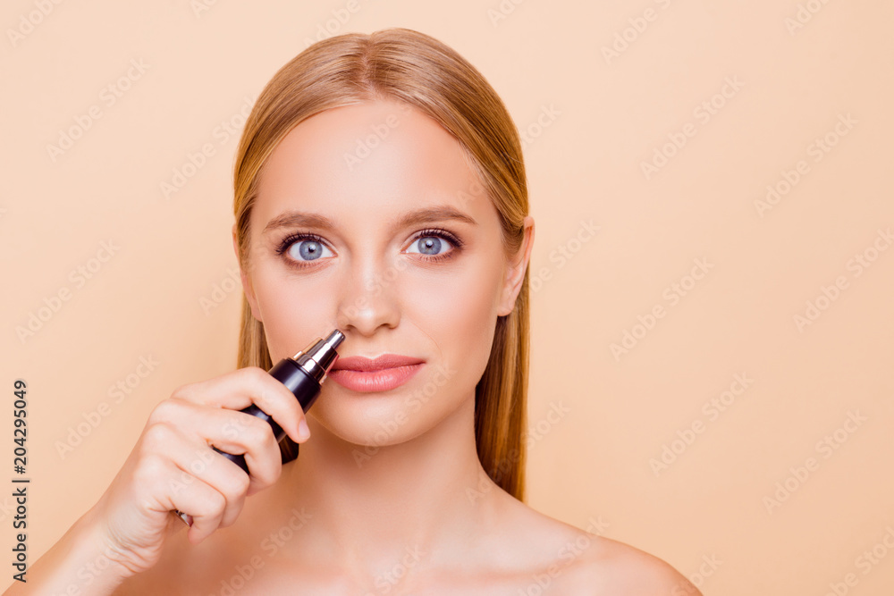 Portrait of natural nude stylish trendy model with flawless skin using special machine on batteries for getting rid on unwanted hair in nostril isolated on beige background looking at camera Portrait of natural nude stylish trendy model with flawless skin using special machine on batteries for getting rid on unwanted hair in nostril isolated on beige background looking at camera