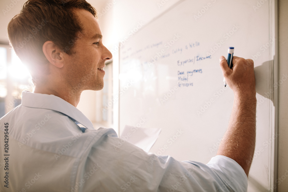 Fototapeta premium Man writing on whiteboard with marker pen