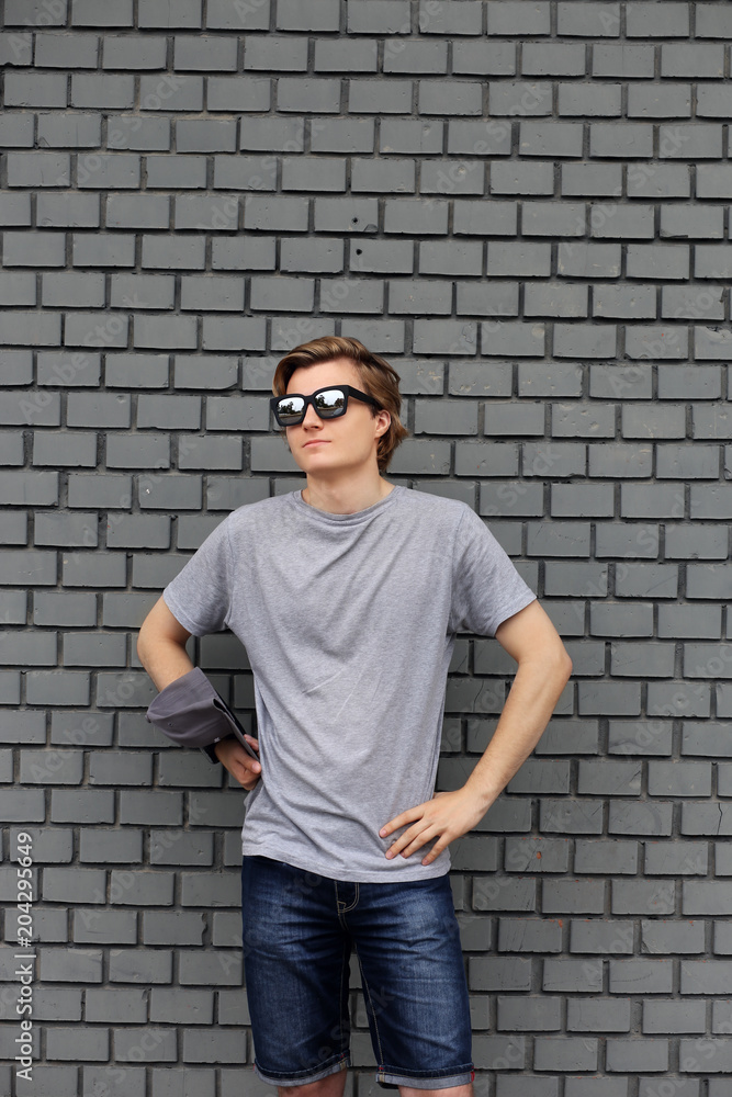 Portrait of attractive teenage boy standing in front of a brick wall. Portrait of attractive teenage boy standing in front of a brick wall.