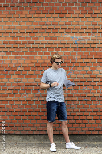Portrait of attractive teenage boy standing in front of a brick wall.