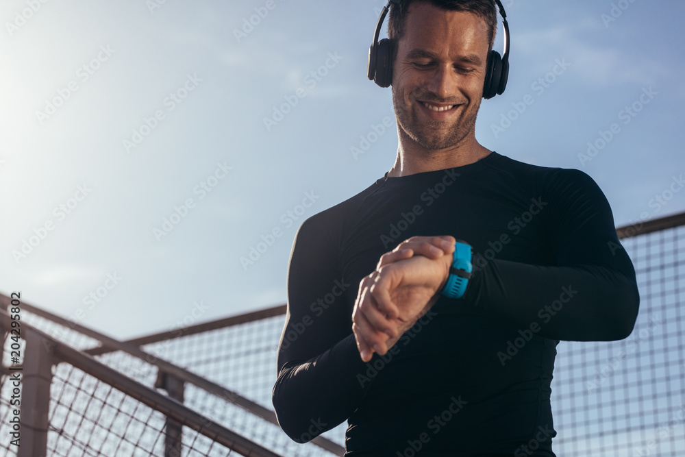 Naklejka premium Athlete using smartwatch to monitor his progress