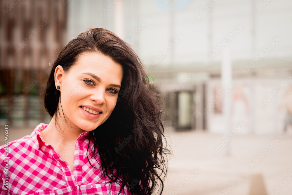 Portrait of a smiling and satisfied woman Isolated on a white background. A young and attractive girl looks ahead against the background of the shopping center. Retro style.