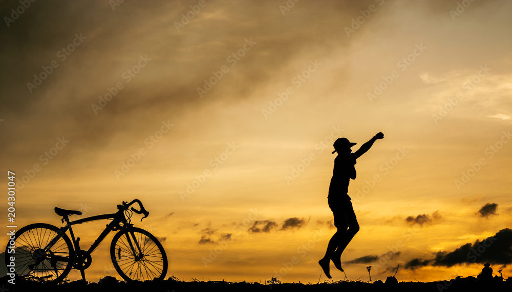 a silhouette of a person jumping in front of a bicycle with a sunset in the background. a silhouette of a person jumping in front of a bicycle with a sunset in the background.