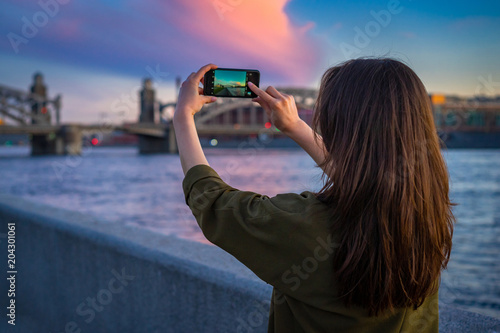 Tourists in Russia. Petersburg. The girl is taking pictures on the phone. The Bridge of Peter the Great. Journey through Petersburg. Bridges of Petersburg.