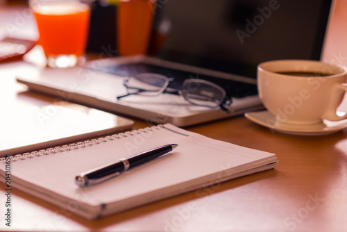 Office table with notepad, computer, pen and coffee cup