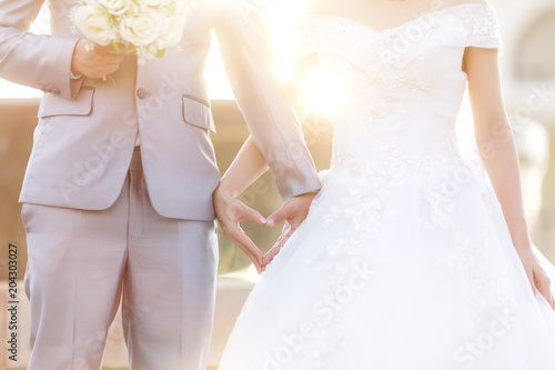 Heart-shaped hands and  wedding dress Bride and groom holding hands