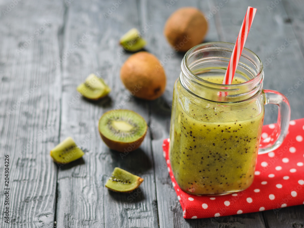 Mug with freshly made kiwi smoothie on a red rag on a rustic black table. Mug with freshly made kiwi smoothie on a red rag on a rustic black table.