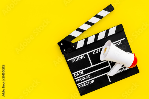 Film director, producer concept. Filming. Electronic megaphone and clapperbord on yellow background top view space for text photo