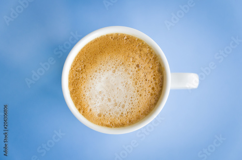 White cup of coffee on light blue background.