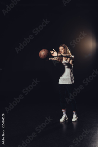man playing with basketball ball, on black
