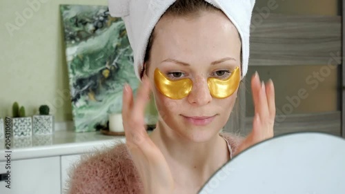 attractive woman spplying cosmetic facial patches at home photo