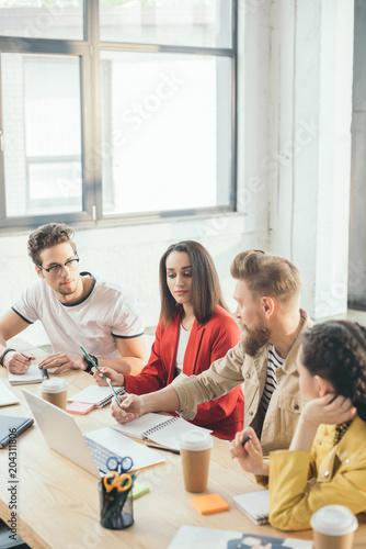 Professional business colleagues men and women by the table with laptop in modern office